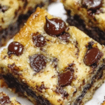 Banana Chocolate Chip Bars: Easy & Delicious Treat for Busy Parents 2 Soft banana chocolate chip bars cut into squares showing moist texture with chocolate chips throughout, arranged on parchment paper with fresh banana slices