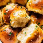 Garlic Bread Rolls: A Quick and Tasty Recipe for Busy Parents 2 Golden brown garlic bread rolls brushed with melted garlic herb butter, arranged in a basket lined with a kitchen towel, showing their soft fluffy texture