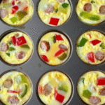 Mini Breakfast Omelets: A Quick and Easy Recipe for Busy Mornings 2 Colorful mini breakfast omelets in a muffin tin with cheese, bell peppers, and herbs, showing their fluffy texture and golden tops